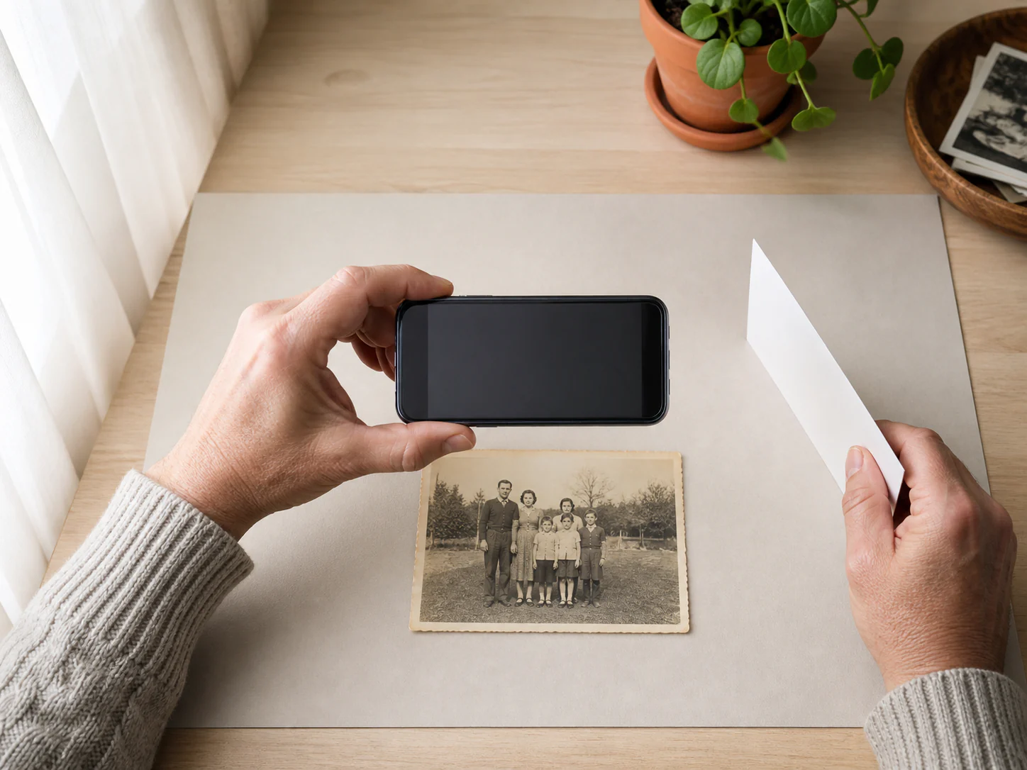 Person photographing an old print flat in soft window light