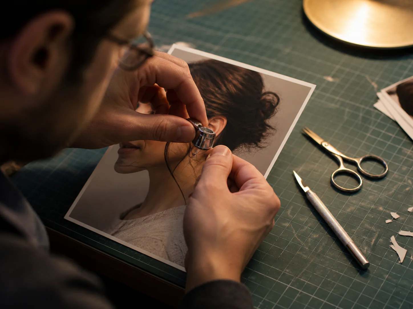 Hands inspecting the edge of a printed portrait with a magnifying loupe